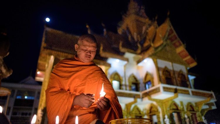 Ein buddhistischer Mönch zündet Kerzen an