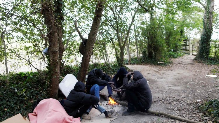 Des migrants soudanais assis autours dans feu dans une forêt à proximité de Calais, le 05 octobre 2017.
