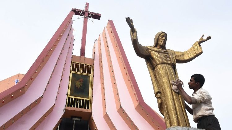 An Indian worker cleans the statue of Jesus ahead Christmas celebrations