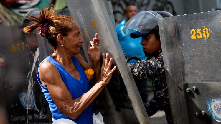 A protester confronts riot police during a protest against food shortage in Caracas