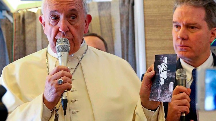 Pope Francis holds a photo of a Japanese boy waiting to cremate the body of his brother in Nagaaki in 1945