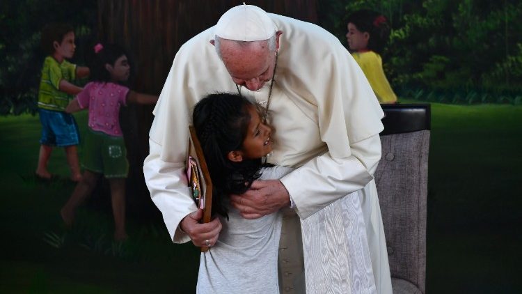 Pope Francis is hugged by a girl during his visit to "The Little Prince" children's home in Puerto Maldonado