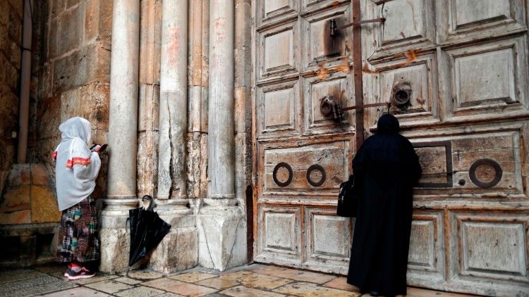 Due donne pregano davanti la porta del Santo Sepolcro a Gerusalemme, chiuso per proteste