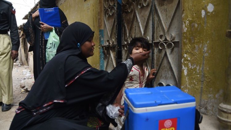 A Pakistani health worker administering polio vaccine drops to a child.