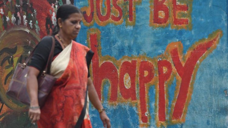 An Indian woman walks past wall graffiti in Mumba