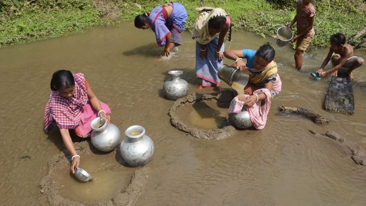 Indische Frauen holen Wasser aus einem kleinen Fluss und filtern Schlamm und Steine