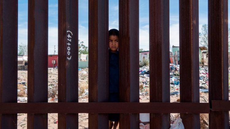 Mexican boy peering over the Border Fence in Anapra, near El Paso, Texas
