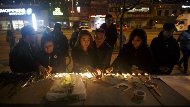 People lay candles and leave messages at a memorial for victims of a vehicular attack in Toronto, Canada