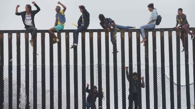 Migrant caravan demonstrators climb the US-Mexico border fence in San Ysidro, California