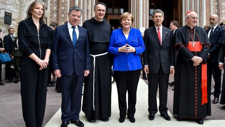Kardināls Agostino Vallini 2018. gada 12. maijā blakus Angelas Merkeles vīram