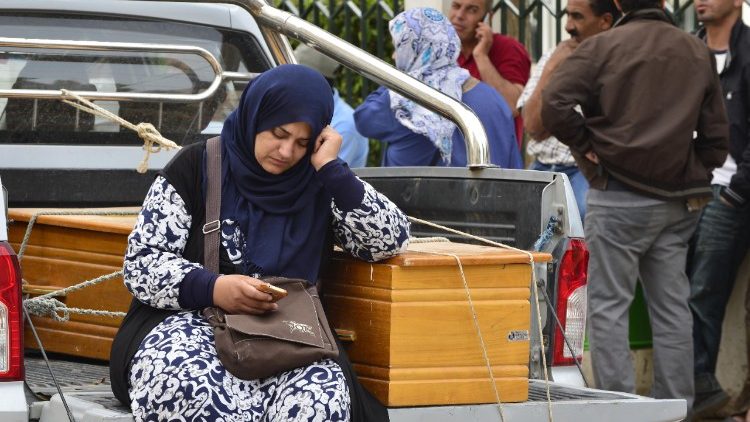 A woman sits next to the coffin of a drowned loved one off the coast of Tunisia