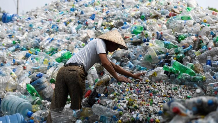 A man sorting through used plastic bottles at a junkyard in Hanoi