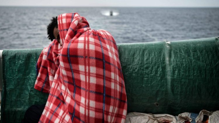 A migrant rests on the deck of a rescue ship after being pulled from the water