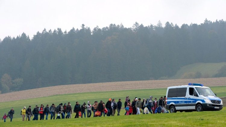 Migrants walk behind a police car on their way from the Austrian-German border to a first registration point of the German federal police in Bavaria 