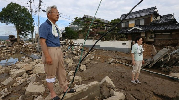 residents look at debris scattered across a flood hit area in Kurashiki