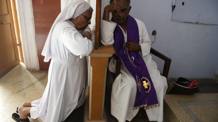 Ein indischer Priester nimmt einer Ordensfrau die Beichte ab