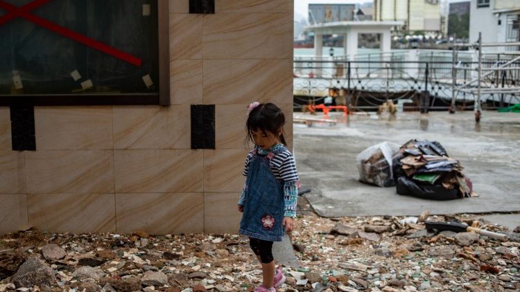 Un bambino cammina sui detriti causati dal tifone Mangkhut
