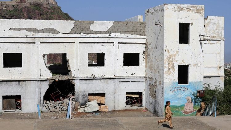 Estudante iemenita, no primeiro dia do novo ano acadêmico, corre ao lado de uma escola semi-destruída por ataques aéreos, na cidade de Taez