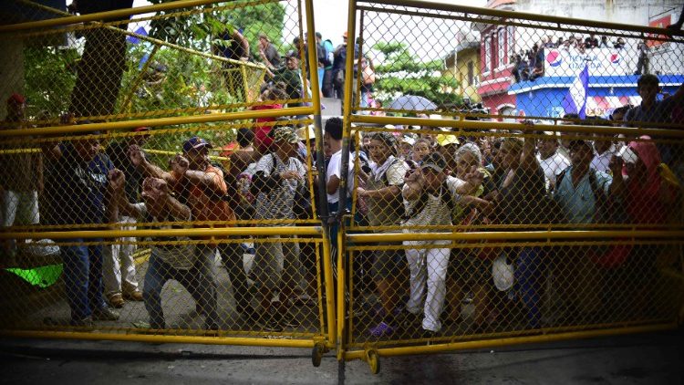Migrants heading to the US try to push through a gate at the Guatemala/Mexico border