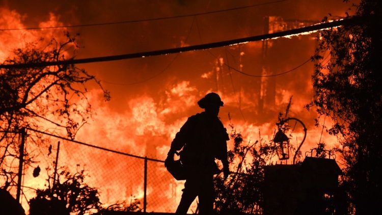 A firefighter silhouetted by a burning home in Malibu, California