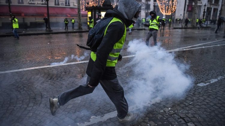 French protesters run as police lob tear gas near the Champs Elysees Avenue