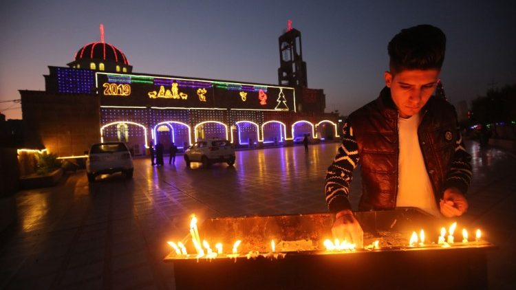 Jovem iraquiano acende uma vela na Igreja de São João, em Qaraqosh, Planície de Nínive