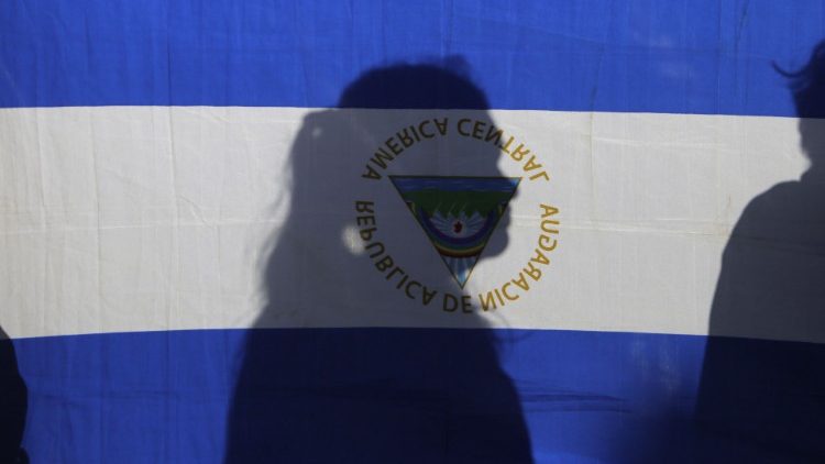 La silhouette d'une femme apparaît à travers un drapeau du Nicaragua lors d'une messe pour la paix, le 1er janvier 2019.