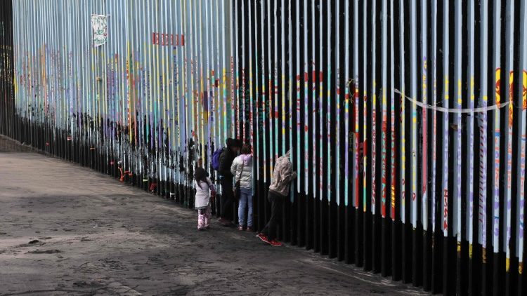 Migrantes no muro que divide México e Estados Unidos