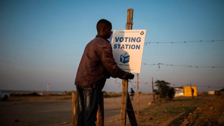 A local resident hangs a sign ahead of elections in an informal settlement on the outskirts of the northern South African city of Polokwane