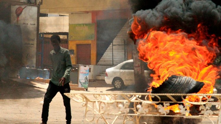 A Sudanese protester walks past a burning tire on a Khartoum street