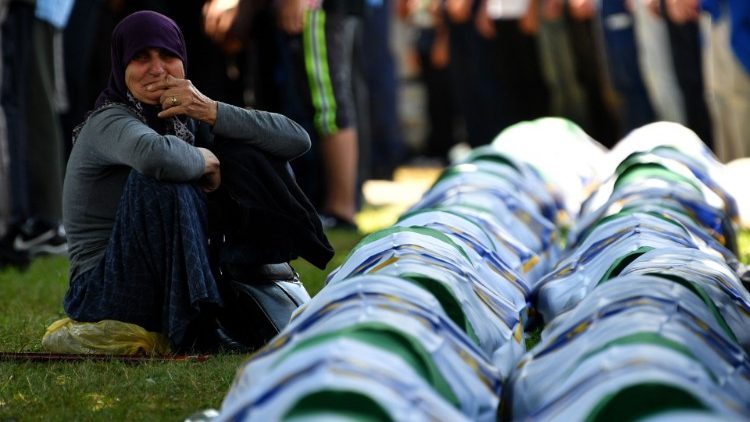 A Bosnian Muslim woman mourns by the caskets of 33 newly identified bodies of the 1995 Srebrenica massacre before their inhumation 