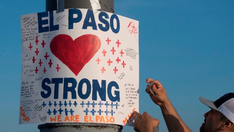 A coach in El Paso, Texas, hangs a sign at a makeshift memorial