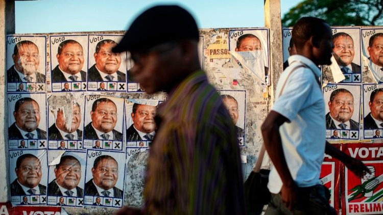 Zwei Männer vor einer Plakatwand mit dem Konterfei des Präsidentschaftskandidaten der Renamo