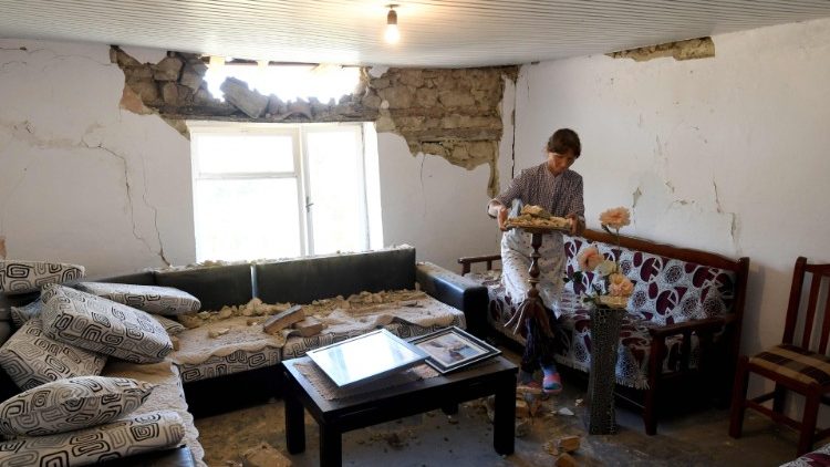 A lady removes a small table from her damaged house in the village of Zhurje near Tirana