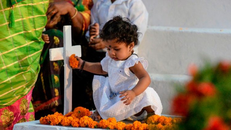 Menina deixa flores em cemitério católico no Dia de Finados em Hyderabad