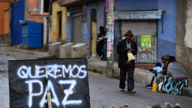 Bolivians resume daily life next to a sign reading "We want peace" in a street of La Paz 