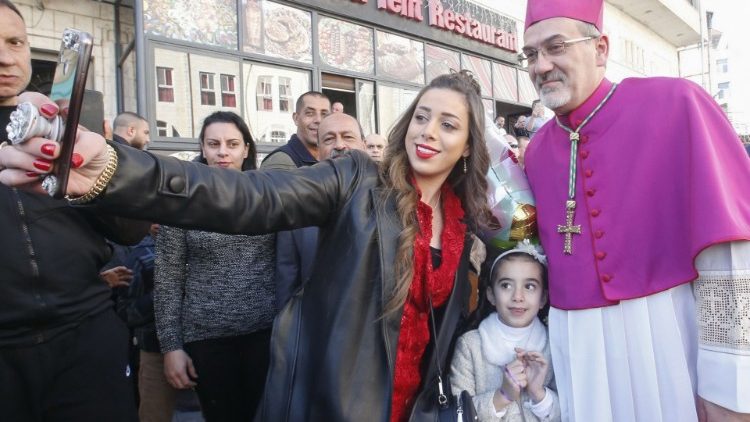 Une femme palestinienne et sa fille prenant un selfie avec Mgr Pizzaballa, le 24 décembre 2019 à Bethléem.