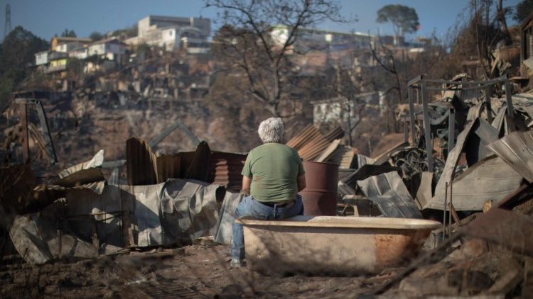A man looks at the destruction caused by a forest fire in Valparaiso, Chile