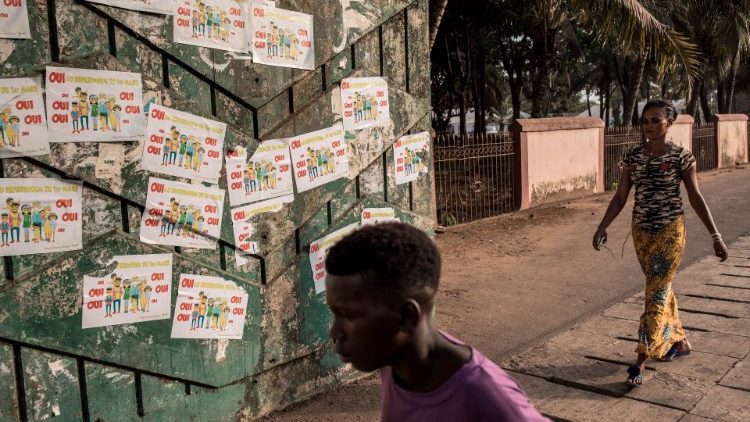 Guineans in Conakry walk in front of posters advertising the Referendum