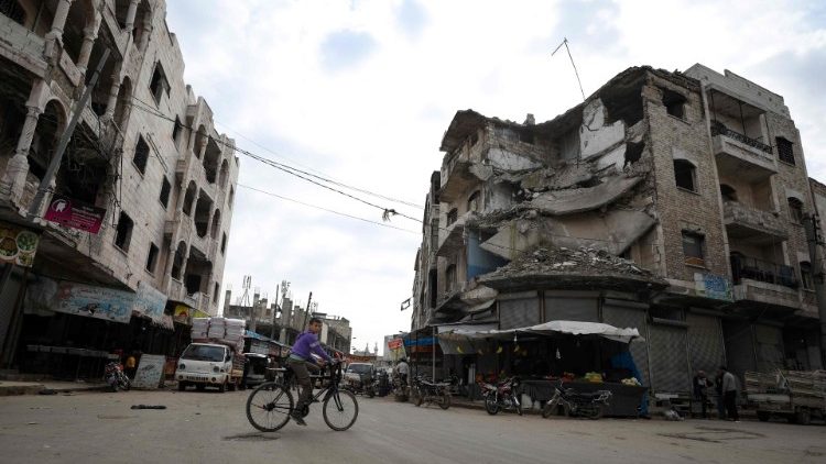 A boy rides his bicycle in front of damaged buildings in the northwestern Syrian city of Idlib