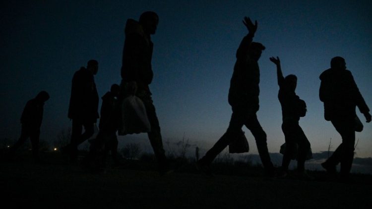 Migrants wave as they walk toward a camp on the Turkey-Greece border