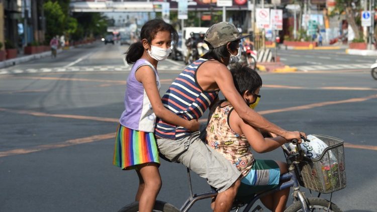 Un père et ses deux enfants dans les rues de Manille, le 20 mars.