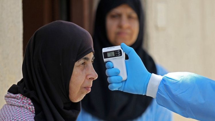Медицинско лице измерва температурата на жена в Ирак