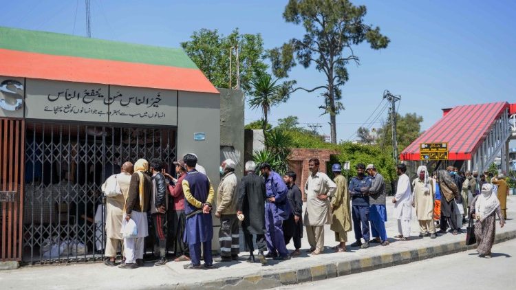 पाकिस्तान में खाद्य सामग्री  लेने के लािए कतार में खड़े लोग
