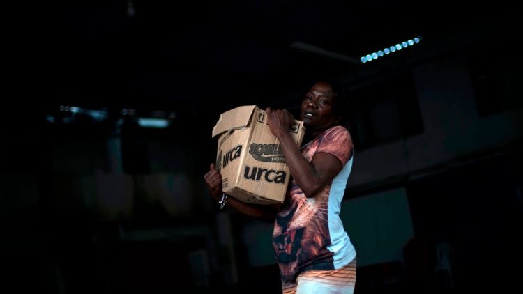 Una mujer lleva una caja con donaciones de alimentos básicos distribuidos por una ONG a las personas que sufren por el coronavirus (COVID-19).