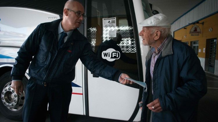 A bus driver gives a face mask to an elderly passenger in Spain