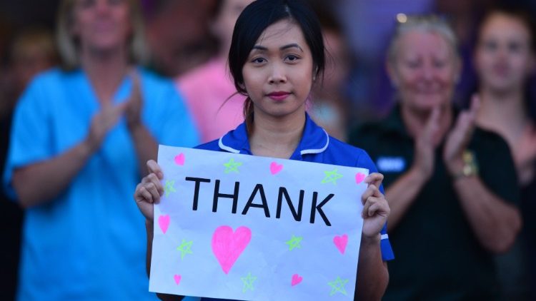 Une employée du "National Health Service", au Royaume-Uni, brandissant un papier de remerciement à l'intention d'un donateur.