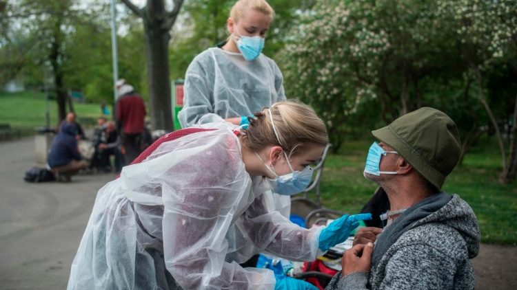 Jovens médicas da Faculdade de Medicina Charles University atendem um sem-teto em praça de Praga