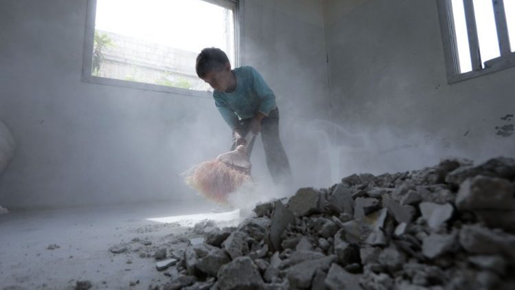Menino sírio ajuda a limpar destroços de sua casa em al-Nayrab