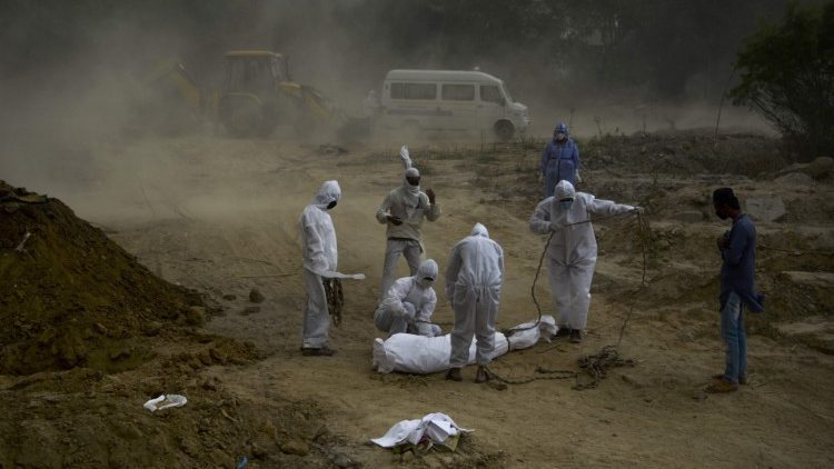 नई दिल्ली में कोविड-19 से मरे व्यक्ति को दफनाते हुए लोग
